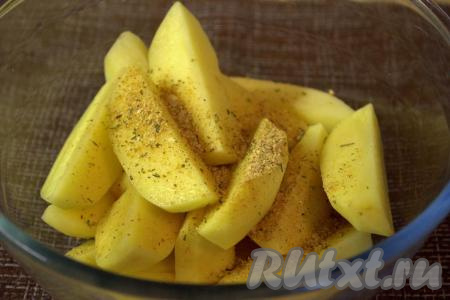 В глубокою миску выложить дольки картофеля, посыпать смесью специй.