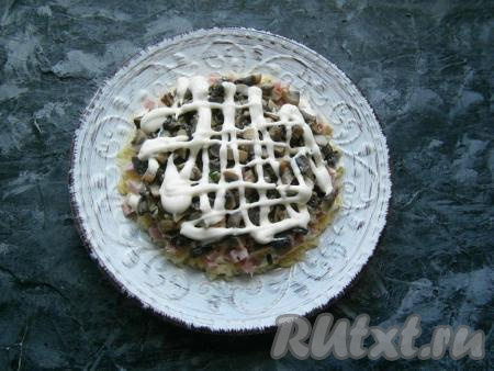 Поверх ветчины равномерно разложить измельчённые маринованные грибы + майонез.