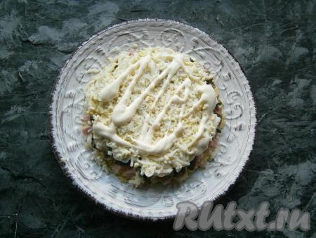 Яйца натереть на тёрке и покрыть ими грибы, нанести сеточку из майонеза.