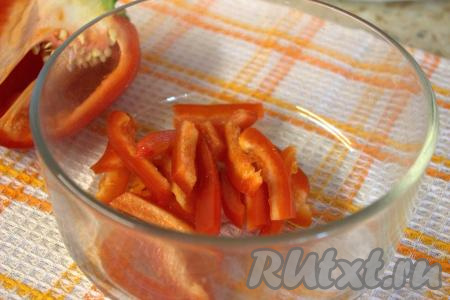 Удалить из болгарского перца перегородки и семена, а затем нарезать его тонкими брусочками и переложить в миску.