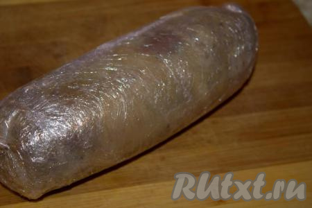 Завёрнутый рулет поместить в миску. Поверх рулета из варёной свиной рульки положить разделочную доску, на которую поставить тяжёлый груз (например, на доску можно поставить банку с водой) и отправить в холодильник. Утром достать рулет из холодильника, снять пищевую плёнку.