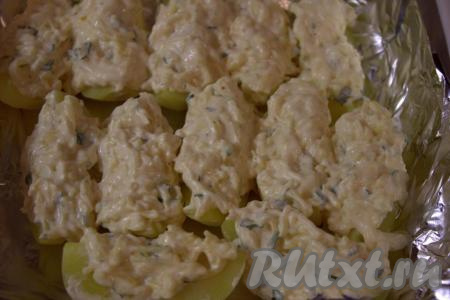 На каждую дольку картошки выложить смесь из сыра, майонеза, чеснока и зелени, затем поставить в заранее разогретую до 180 градусов духовку и запекать 25-30 минут (до готовности  - готовая картошка будет легко прокалываться вилкой). Продолжительность запекания зависит от сорта картофеля.