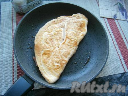 Жарить омлет с ветчиной и сыром на медленном огне минуты 2-3, накрыв сковороду крышкой, после чего его перевернуть и готовить ещё 2-3 минуты под крышкой.