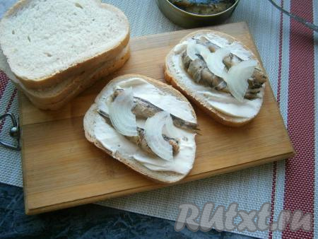 Поверх каждой рыбки разложить по 2 тонких полуколечка очищенного репчатого лука.