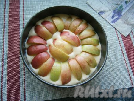 Выложить в форму тесто, сверху разместить дольки яблок без семян кожурой кверху, как на фото.