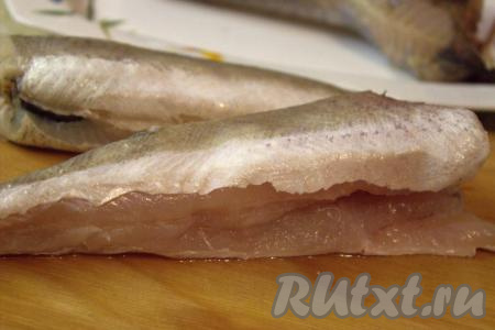 Замороженного хека разморозить, отрезать плавники, удалить из брюшка чёрную плёнку.