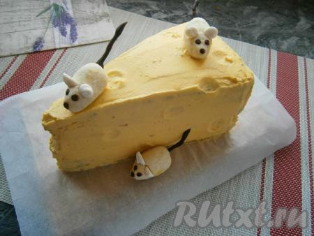 Когда торт стабилизируется, выровнять его оставшимся жёлтым кремом и снова поместить в холодильник на пару часов. Имитировать дырки можно с помощью маленьких мерных ложечек или просто оставить в таком виде - торт и так похож на кусок сыра. Расположить произвольно мышек на сыре, вставив им хвостики из шоколада.