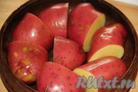 Картофель хорошо вымыть. Для этого блюда лучше брать крупную картошку или картофелины, примерно, одинакового размера. Я готовила молодой картофель, поэтому не очищала его от кожуры. Если у вас картошка не молодая, её лучше очистить. Разрезать крупные картофелины на две части (если картошины среднего размера - оставьте их целыми) и выложить в жаропрочную форму.