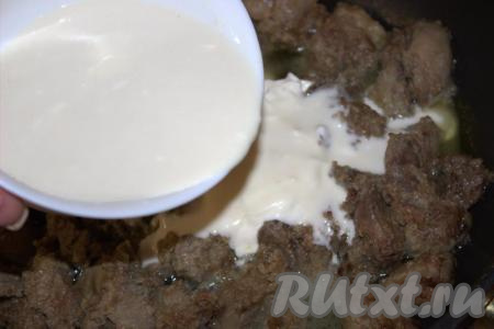 Влить тонкой струйкой в сковороду к печёнке приготовленную смесь из сметаны и муки, аккуратно перемешать.