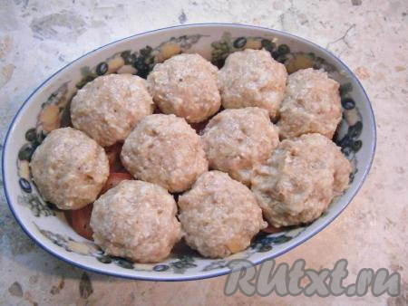 Влажными руками из фарша сформировать достаточно большие тефтели и выложить их на помидоры.