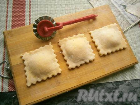 Квадраты с начинкой накрыть квадратами из теста, на которые не выкладывали начинку, прижать края. По желанию, обрезать края равиоли фигурным ножом.