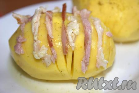 В каждый разрез картошин поместить по ломтику бекона. Картошку посолить и приправить по вкусу специями.