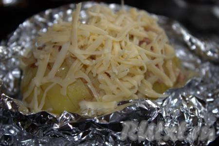 Готовую картошку-гармошку с беконом достать из духовки. Фольгу аккуратно развернуть и посыпать каждую картофелину сыром, натёртым на мелкой тёрке, и измельчённым укропом.