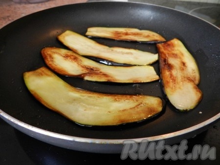 В сковороде разогреть растительное масло, выложить несколько ломтиков баклажанов в один слой и обжарить их до румяности с двух сторон.