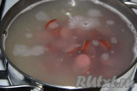 Когда картошка с рисом проварятся минут 10, добавить в суп нарезанные копчёные колбаски и варить 5 минут.