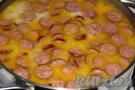 Если добавляете плавленный сыр, то самое время его положить и хорошо перемешать. Потомить суп с копчёными колбасками до полного растворения сыра. Если не добавляете сыр, то просто проварите суп несколько минут. 