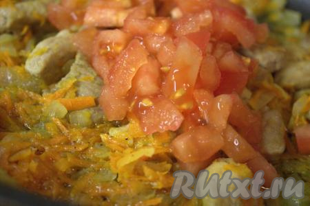 Добавить нарезанный помидор в сковороду к овощам и свинине, перемешать и тушить 2-3 минуты.