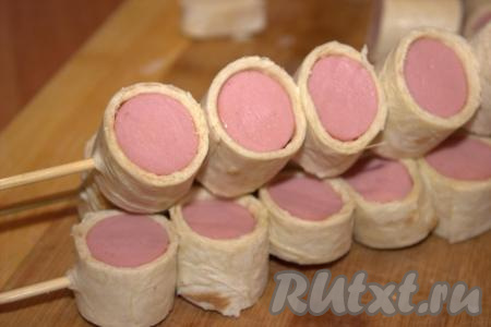 Кусочки сосисок в лаваше нанизать на шпажки, как шашлык.