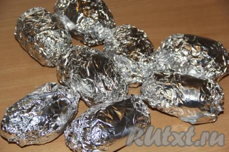 Плотно завернуть каждую&nbsp;картофелину&nbsp;в фольгу, выложить на противень и запекать в разогретой духовке, примерно, 45-55 минут при температуре 250 градусов. Время запекания зависит от размера картофеля (готовность можно проверить с помощью зубочистки - готовая картофелина будет легко прокалываться). 