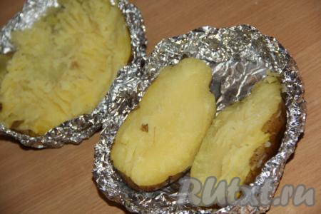 Готовый картофель достать из духовки, развернуть, формируя из фольги, в которой запекалась картошка, круглую тарелочку. Разрезать каждую картофелину на две части.