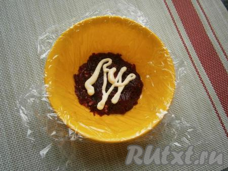 Небольшую глубокую мисочку или салатник (у меня диаметром 12 см) застелить пищевой плёнкой. Выложить 1/3 часть&nbsp;свеклы с орехами, утрамбовать, смазать майонезом.