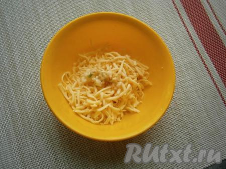 Сыр натереть на средней (или мелкой) тёрке, добавить пропущенный через пресс чеснок, перемешать.