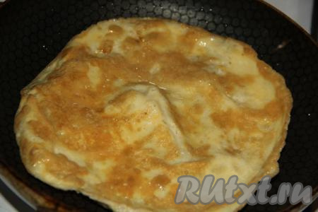 Когда яичный блинчик поджарится с одной стороны, перевернуть его, поджарить с другой стороны, а затем выложить на тарелку. Таким же образом приготовить блинчик из второго яйца.