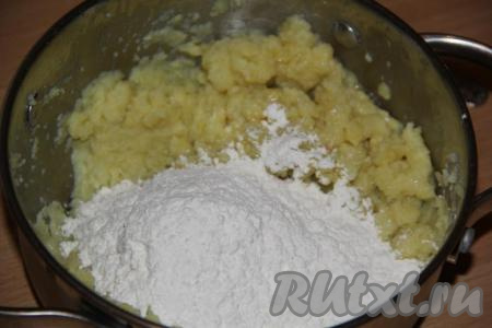 Начать постепенно добавлять муку, каждый раз хорошо вмешивая её в картофельную массу. Вначале перемешивать тесто ложкой.