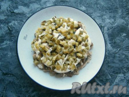 Смазать этот слой майонезом и выложить следующим слоем нарезанный маленькими кубиками маринованный огурчик.