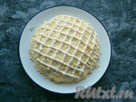 С помощью кулинарного одноразового мешка с чуть обрезанным кончиком нанести сверху салата ровную сетку из майонеза.