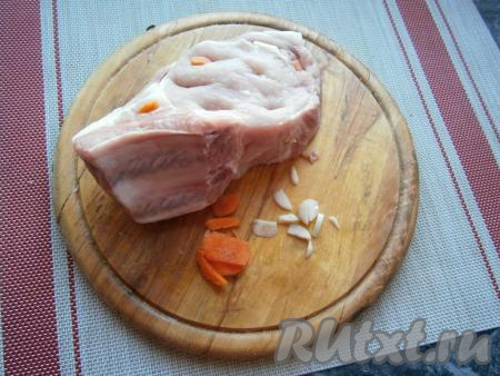 Чеснок и морковь очистить. Кусок свинины вымыть, обсушить и нашпиговать кусочками чеснока и морковки.