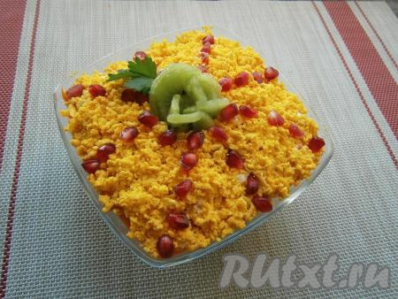 Смазать морковь майонезом и посыпать весь салат "Африка" сверху натёртыми желтками. Украсить салат зёрнами граната и розочкой из оставленных кружочков киви.