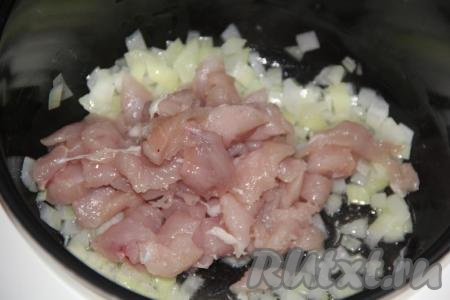 Нарезать куриное филе на средние кусочки и выложить к луку в чашу мультиварки.