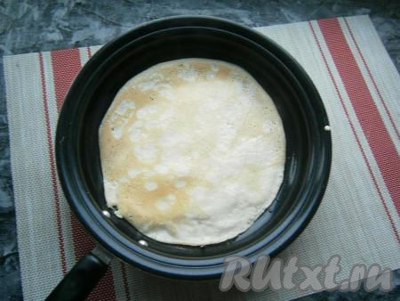 Перед жаркой первого блина сковороду (я жарила на сковородке диаметром 22 см) нужно немного смазать растительным маслом и хорошо разогреть. Налить на сковороду часть теста, равномерно распределить и жарить блин вначале с одной стороны на среднем огне до румяности, затем перевернуть и жарить до румяности с другой стороны. Переложить блинчик на тарелку. Далее можно не смазывать сковороду маслом, так как наше блинное тесто в своем составе уже содержит растительное масло. Таким образом пожарить все блины, у вас получится 8-9 достаточно тонких блинов.