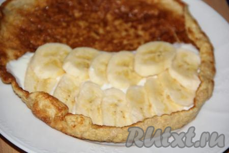 Банан очистить и нарезать тонкими кружочками. Выложить плотным слоем банан на творожок.