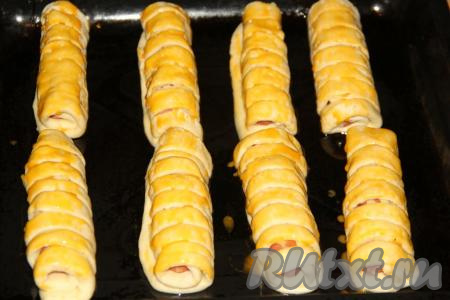 Подготовленные заготовки сосисок&nbsp;в тесте выложить на противень, смазанный растительным маслом, и оставить на 35 минут в тепле. Затем смазать тесто взбитым яичным желтком.