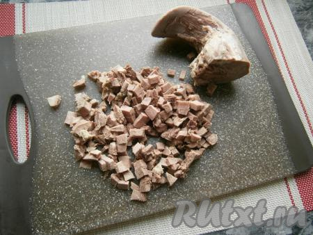 Поместить язык в кастрюлю, залить чистой холодной водой, поставить на огонь, дать воде закипеть. Варить язык, после закипания воды, около 1,5 часов на небольшом огне. Затем залить его холодной водой минут на 15 и очистить от толстой кожицы. Дать языку полностью остыть. Говяжий язык будет вариться дольше - около 3 часов. Нарезать язык маленькими кусочками-кубиками.