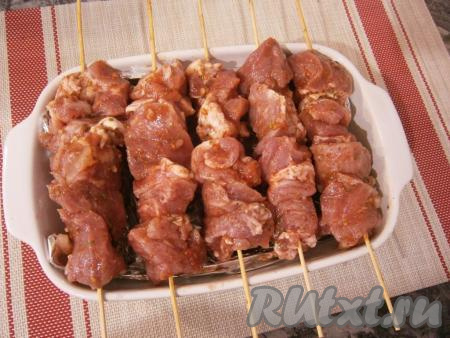 Миску накрыть крышкой и оставить мясо с помидорами и луком&nbsp;в прохладном месте на 4-5 часов, а лучше - на всю ночь.&nbsp;Деревянные шпажки предварительно замочить в горячей воде на 10-15 минут (чтобы не горели в духовке) и нанизать на них замаринованную в томате свинину. Шпажки расположить на прямоугольной форме для запекания, в которую налить воду (на 1/3 объема).