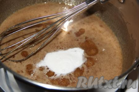 Как только сахар полностью растворится, снять кастрюлю с огня и всыпать соду. Тщательно перемешать с помощью венчика, масса начнёт увеличиваться в объёмах. Она станет пышной и пузырчатой. Добавить в кастрюлю мягкое масло и хорошо перемешать, масса&nbsp;сразу осядет, а масло полностью растворится. Слегка остудить массу.