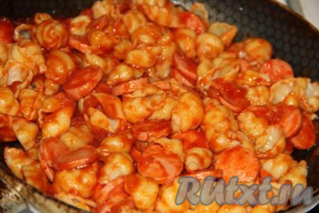 Перемешать макароны с сосисками и соусом, накрыть сковороду крышкой и потомить 3-4 минуты.