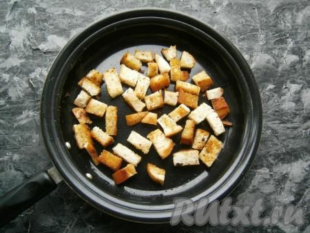 Обжарить батон на среднем огне, перемешивая, до золотистого цвета и до тех пор, пока кусочки батона не станут сухими. Дать сухарикам остыть.