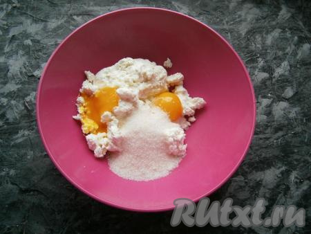 Для приготовления шариков в творог добавить сырые желтки, всыпать сахар.