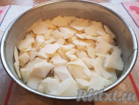 Смазать сливочным маслом форму для выпечки (у меня форма диаметром 25 см), нарезать яблоки кусочками и равномерно распределить их по дну формы.