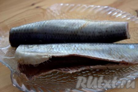 Замороженную сельдь поместить в герметичный пакет и отправить для оттаивания в холодильник на 7-8 часов (время размораживания зависит от размера рыбы). Рыба медленно разморозится, останется плотной и хорошо будет очищаться. Затем у сельди отрезать хвост и голову. Острым ножом разрезать брюшко, удалив все внутренности и чёрную плёнку&nbsp;внутри стенок брюшка.