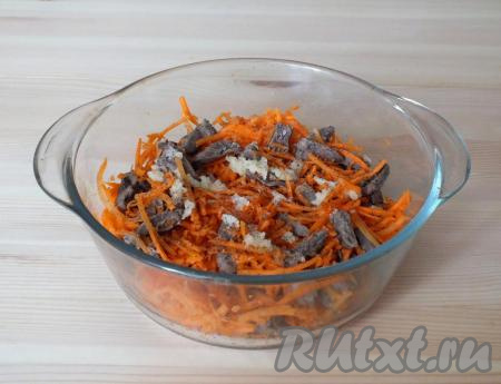 К моркови добавьте охлаждённые сердечки, чёрный молотый перец и чеснок, пропущенный через пресс, перемешайте.