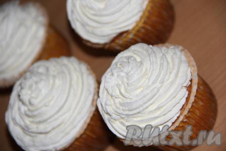 Охлаждённые сливки (я использую сливки на растительных маслах) взбить миксером до стойких пиков, затем переложить в кондитерский мешок и отсадить на остывшие кексы пышной шапкой.