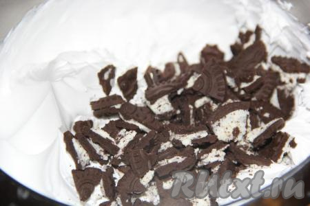 Печенье поломать и добавить во взбитые сливки, перемешать получившийся крем. 1/3 часть крема сразу отложить в отдельную ёмкость и отправить в холодильник (этот крем потребуется на следующий день для украшения боков и верха торта).