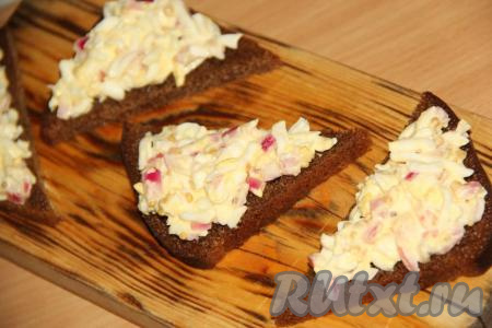 Выложить салат из яиц и маринованного лука на кусочки чёрного хлеба.