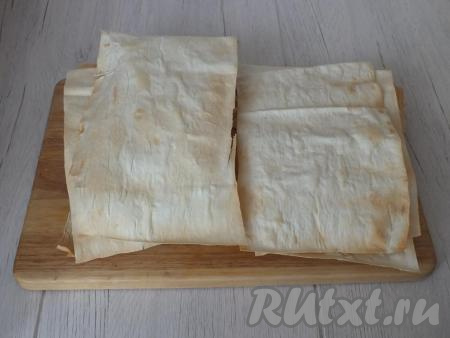 Подсушенные листы лаваша переложите на доску друг на друга, не прижимая. Проделайте подобный процесс со всеми листами лаваша. Когда подсушенные коржи остынут, выберите из общего количества два наиболее "неприглядных" листа, в дальнейшем они станут крошкой для посыпки торта.