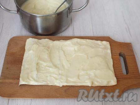 Далее соберите торт "Наполеон", для этого возьмите доску (или прямоугольное просторное блюдо). Выложите на него одну заготовку из лаваша. Сверху положите 2-3 столовые ложки с горкой заварного крема и распределите по коржу.